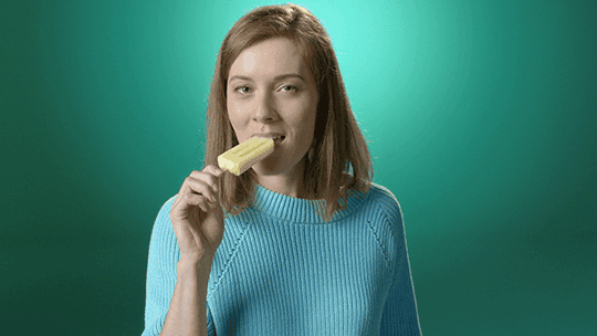 Frau ist ein gelbes Capri Eis und lächelt